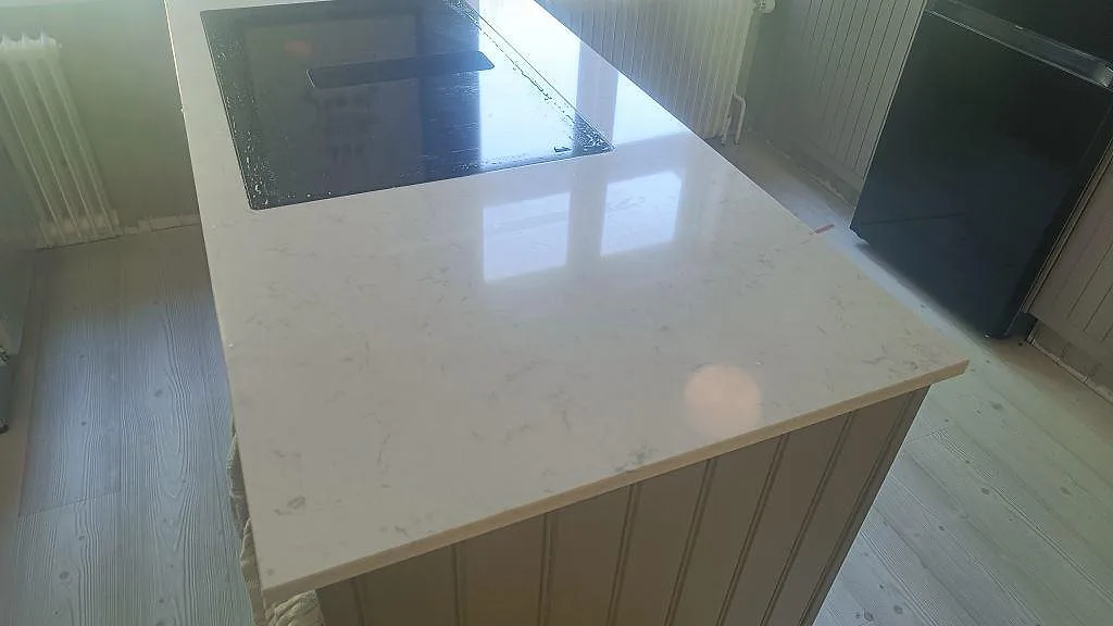 Polerad Silestone Lagoon på köksö med svart häll och synlig ljus komposityta i Mariestad.
