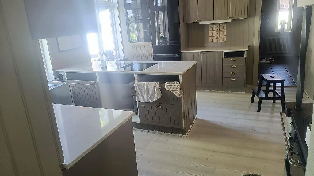 Köksbänkskiva i polerad Silestone Lagoon, 20 mm, med köksö, svart häll och ljusa bänkytor i Mariestad.