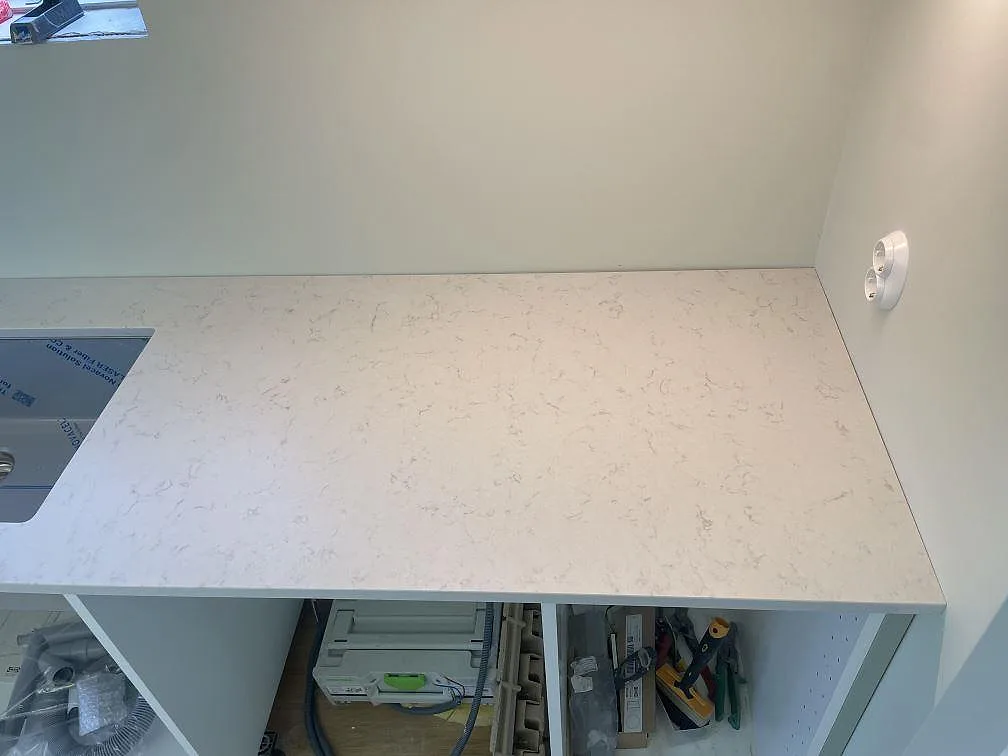 Närbild av bänkskiva i vit Silestone Lagoon med matt Mocka-yta och mjuk grå ådring längs köksvägg i Nyhamnsläge.