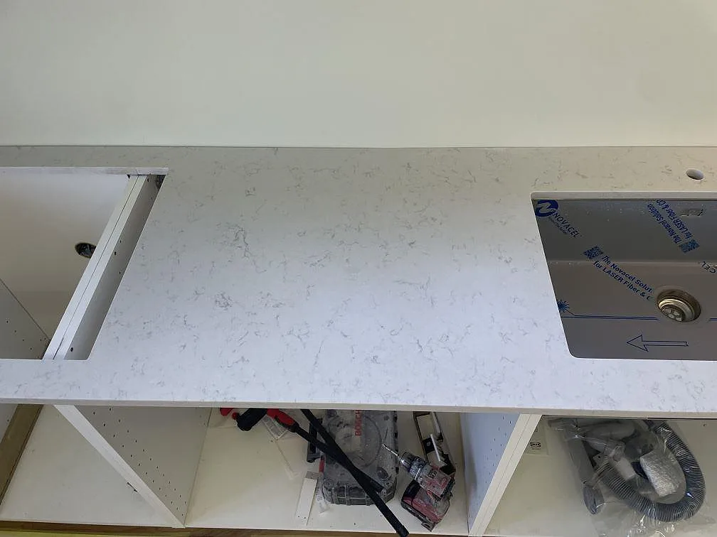 Köksbänkskiva i Silestone Lagoon med matt Mocka-yta, diskho och förberedd hällöppning över vita stommar i Nyhamnsläge.