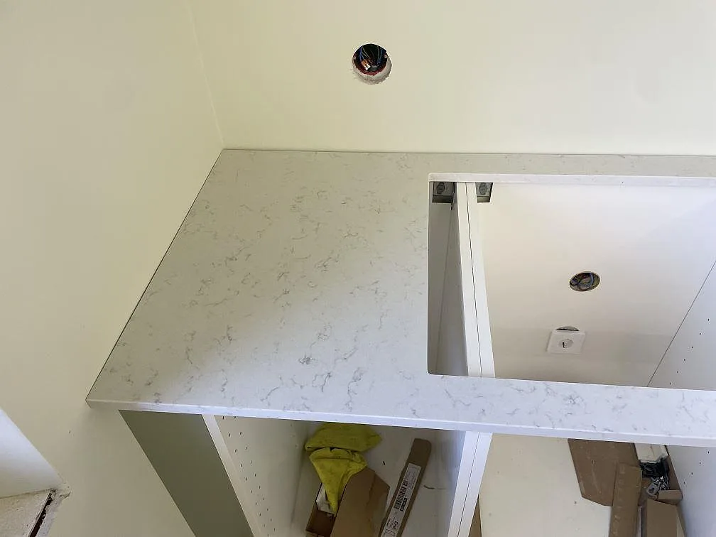 Detalj av matt Silestone Lagoon bänkskiva vid hällöppning, vit kvartskomposit med mjuk ådring i ett kök i Nyhamnsläge.
