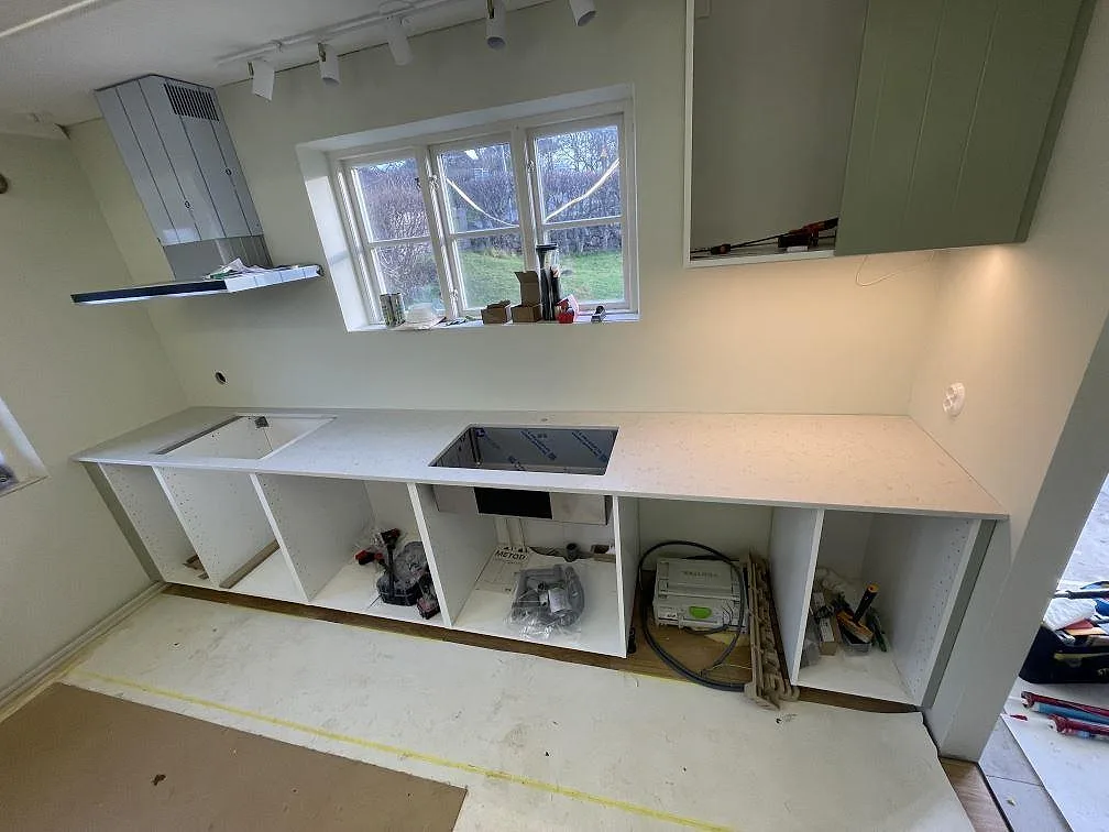 Köksbänkskiva i vit Silestone Lagoon, matt Mocka-yta, med diskho och hällöppning i ett kök under montering i Nyhamnsläge.