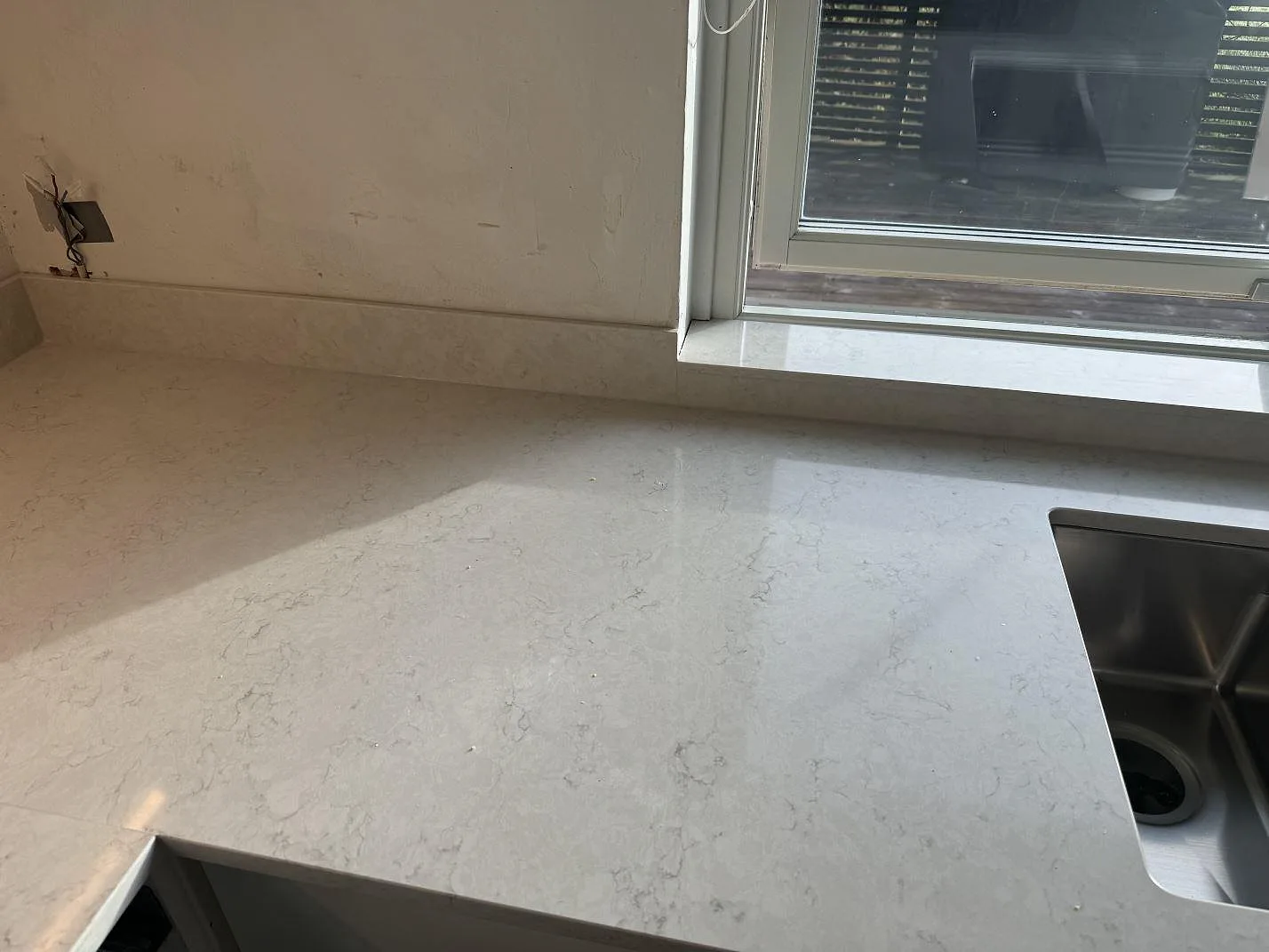 Polerad köksbänkskiva i Silestone Lagoon med fönsternisch, stänkskydd och synlig diskho i Pixbo.