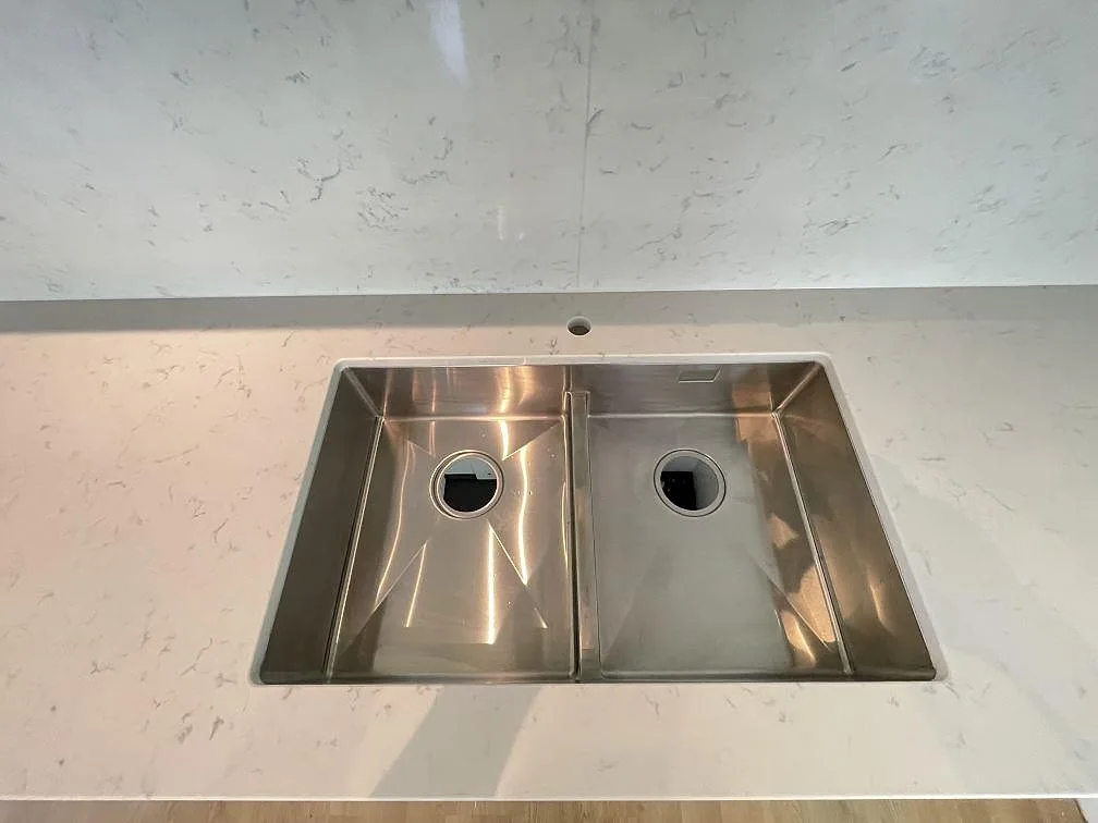 Underlimmad rostfri dubbelho i en vit Silestone Lagoon köksbänkskiva, sedd ovanifrån, i Tävelsås.