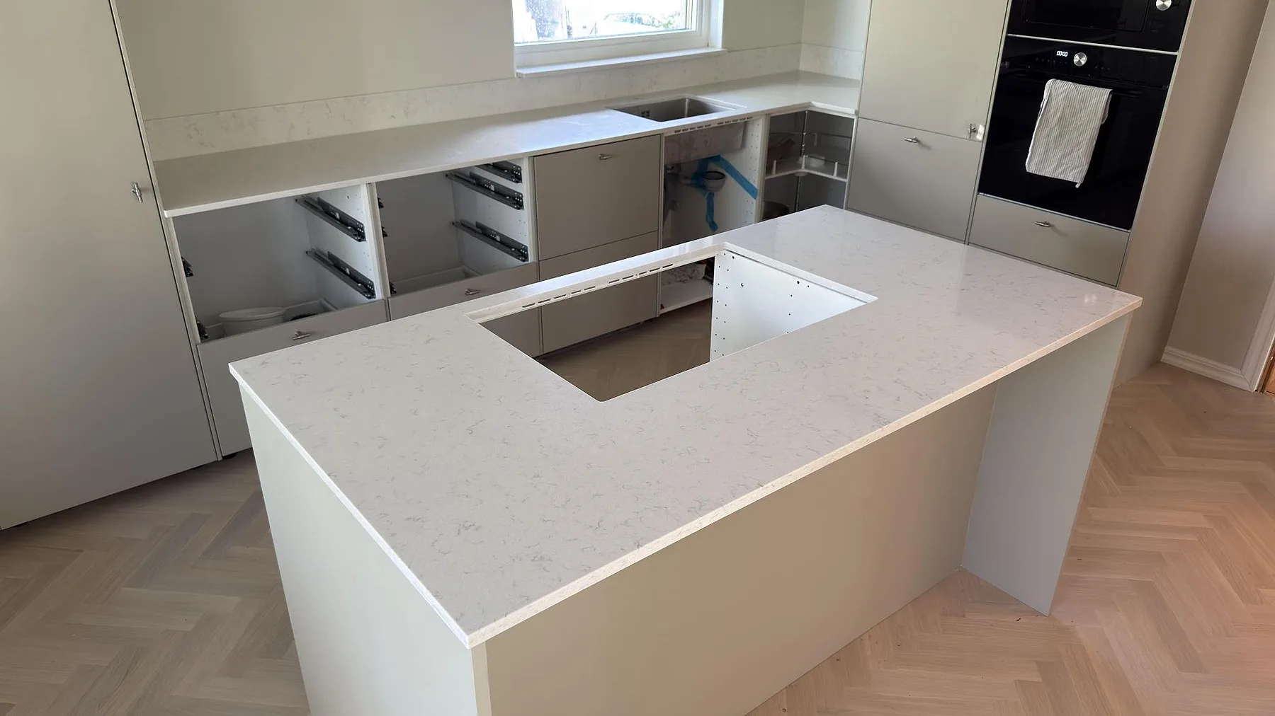 Köksbänkskiva och köksö i polerad Silestone Lagoon i ett kök under montering på Värmdö.