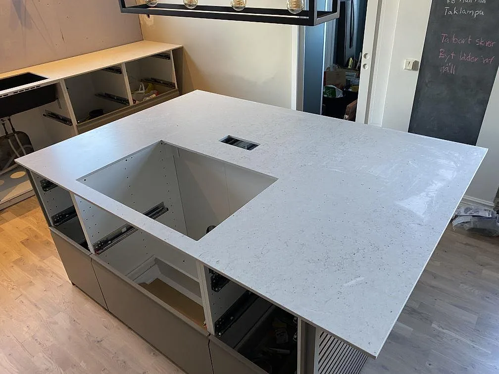 Närbild på köksö i Silestone Lime Delight, Mocka, med öppet urtag och ljus komposityta under montering i Anderslöv.