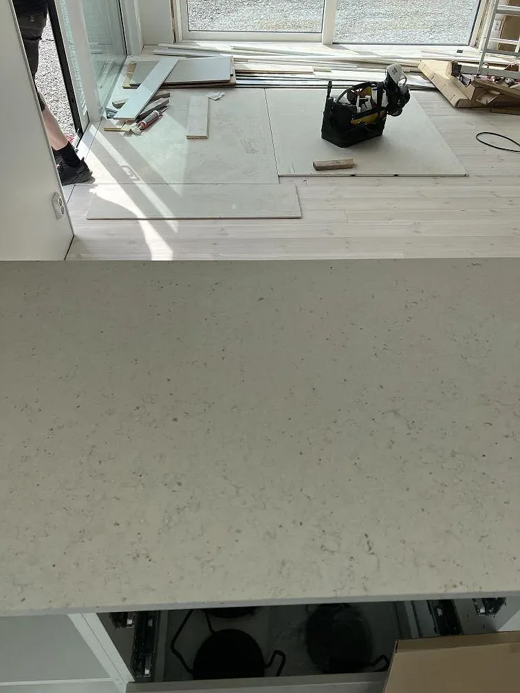 Närbild av matt Silestone Lime Delight komposit på köksbänk under montering, med fönsterljus och öppna stommar i Borgholm.