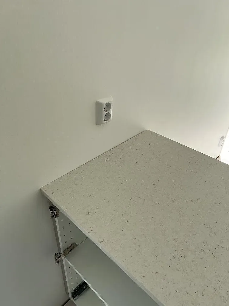 Detalj av matt Silestone Lime Delight på separat bänk med eluttag och öppen köksstomme i Borgholm.