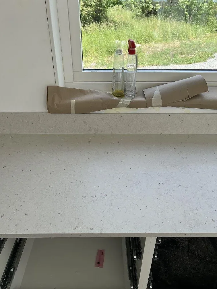 Silestone Lime Delight bänkskiva med låg stänkkant framför fönster och trädgårdsutsikt i köket i Borgholm.