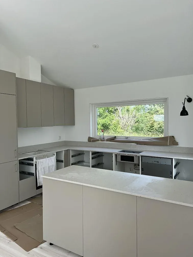 Köksbänkskivor i ljus Silestone Lime Delight, matt Mocka, längs fönstervägg och bänkdel i ett kök i Borgholm.