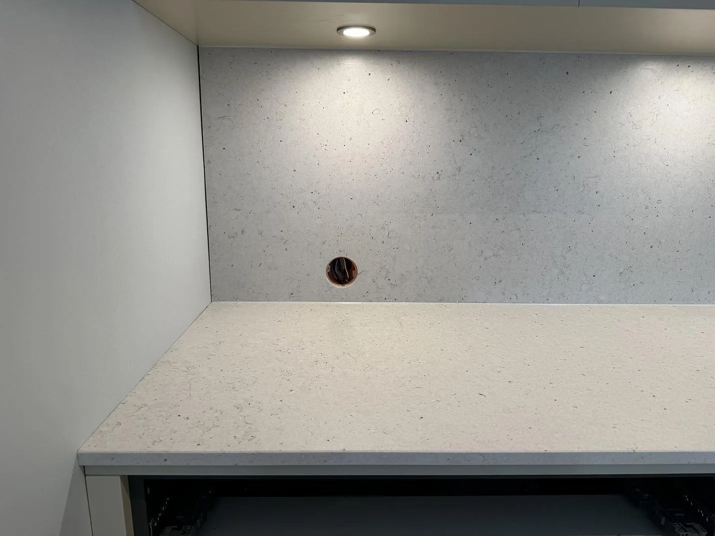 Bänkskiva och stänkskydd i Silestone Lime Delight, matt kvartskomposit, belyst under väggskåp i ett kök i Höganäs.