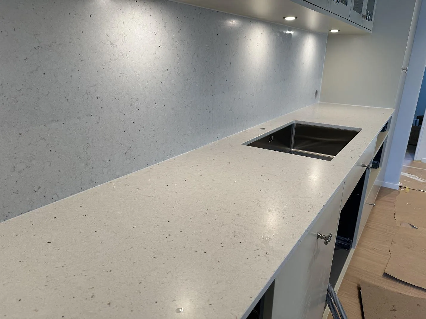 Väggbänk i Silestone Lime Delight, matt Mocka, med rostfri diskho och stänkskydd under väggskåp i Höganäs.