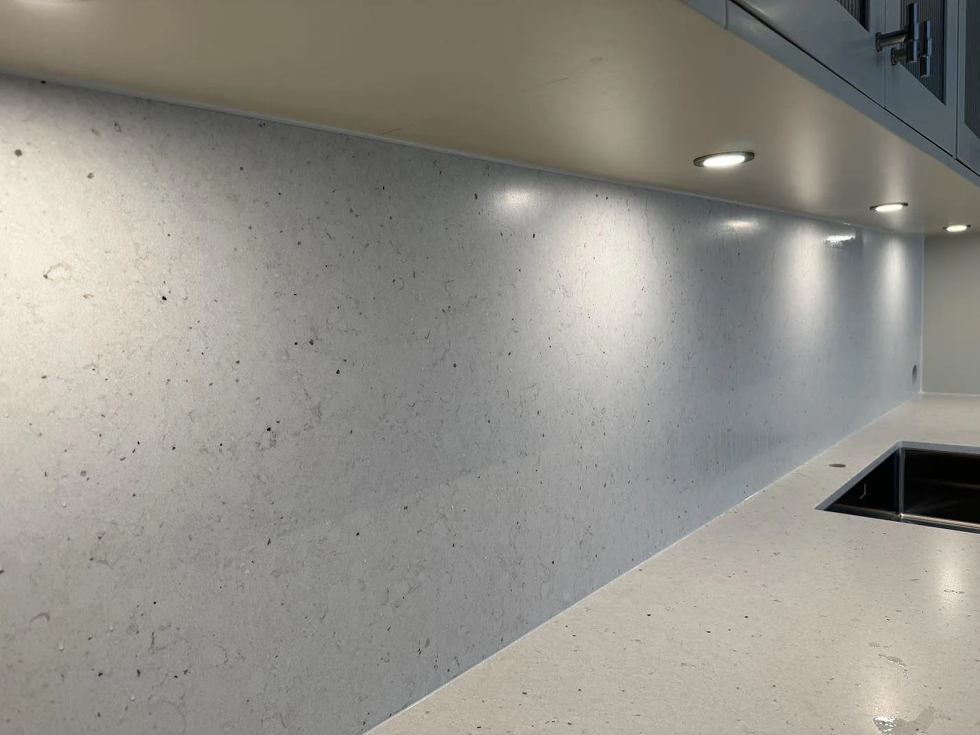 Närbild på stänkskydd och bänkskiva i Silestone Lime Delight, matt kompositsten, vid rostfri diskho i Höganäs.