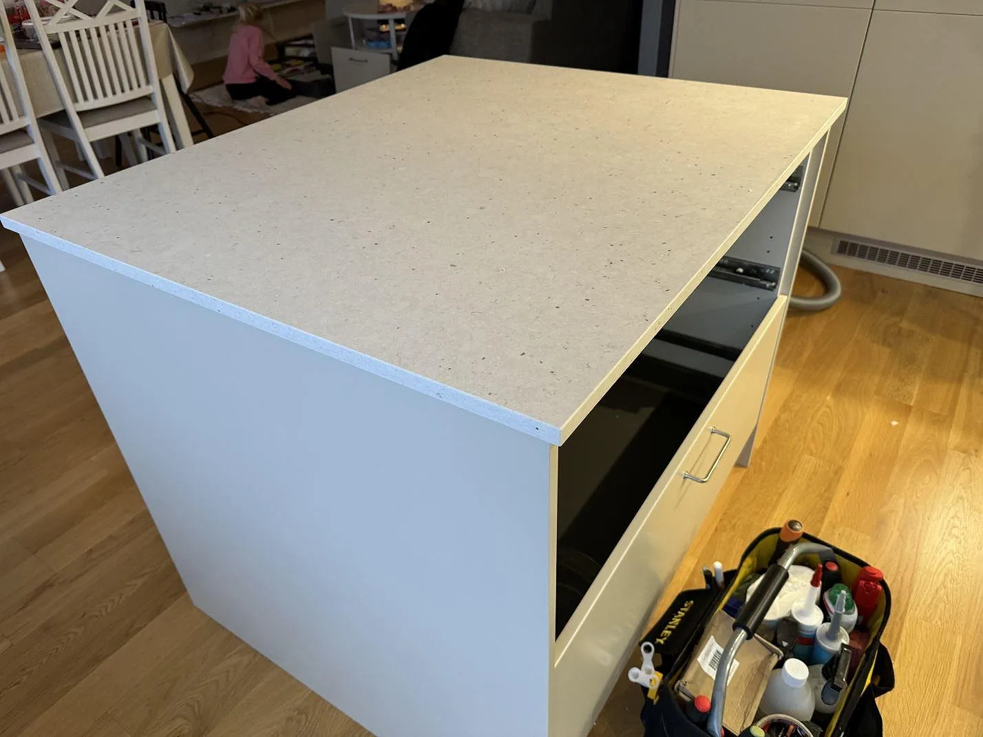 Köksö med stor sammanhängande Silestone Lime Delight-skiva, matt Mocka-yta och vita stommar under montering i Lidköping.