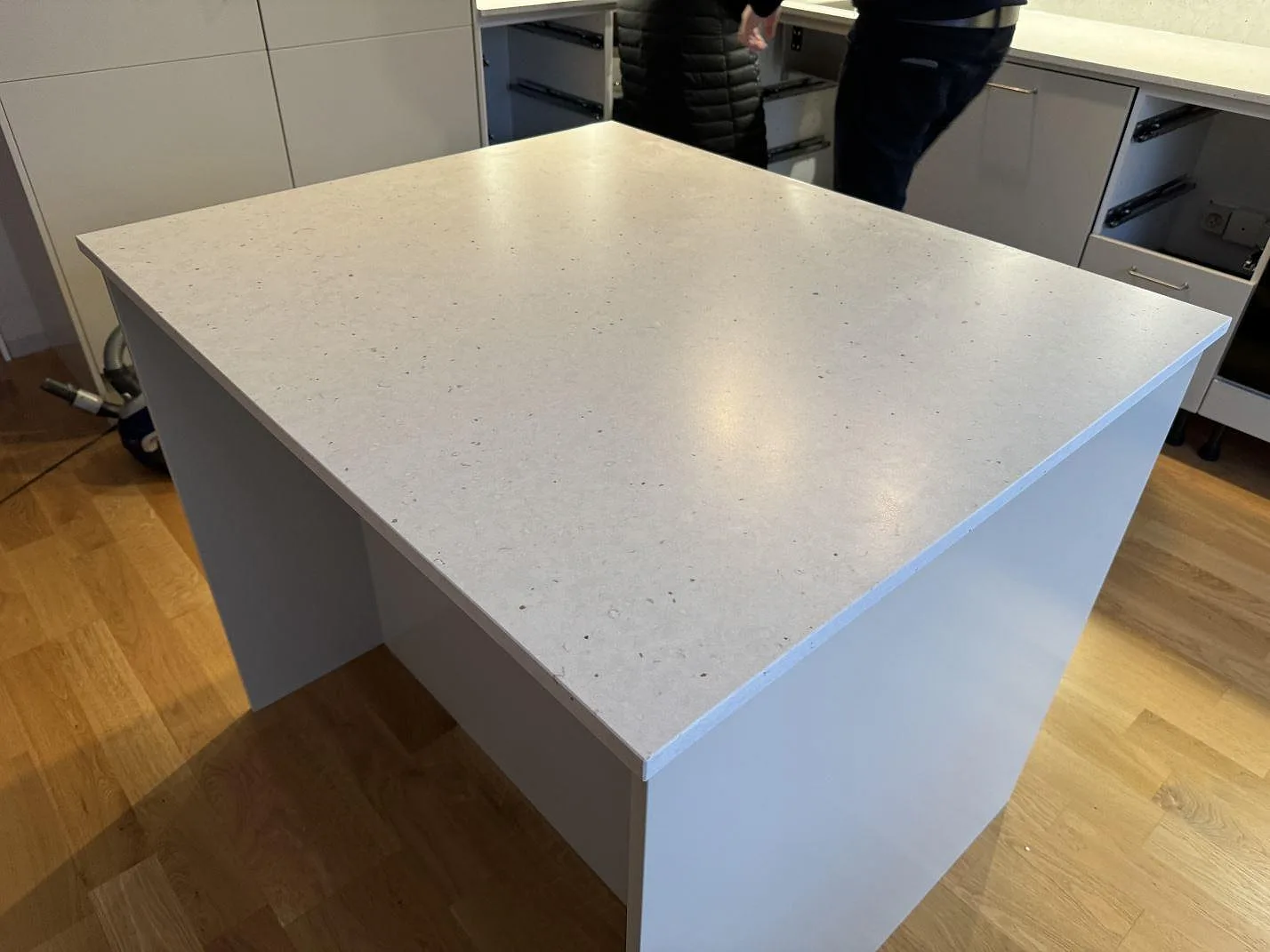 Köksö i Silestone Lime Delight, matt kvartskomposit med diskret grå ådring, monterad framför vita köksskåp i Lidköping.