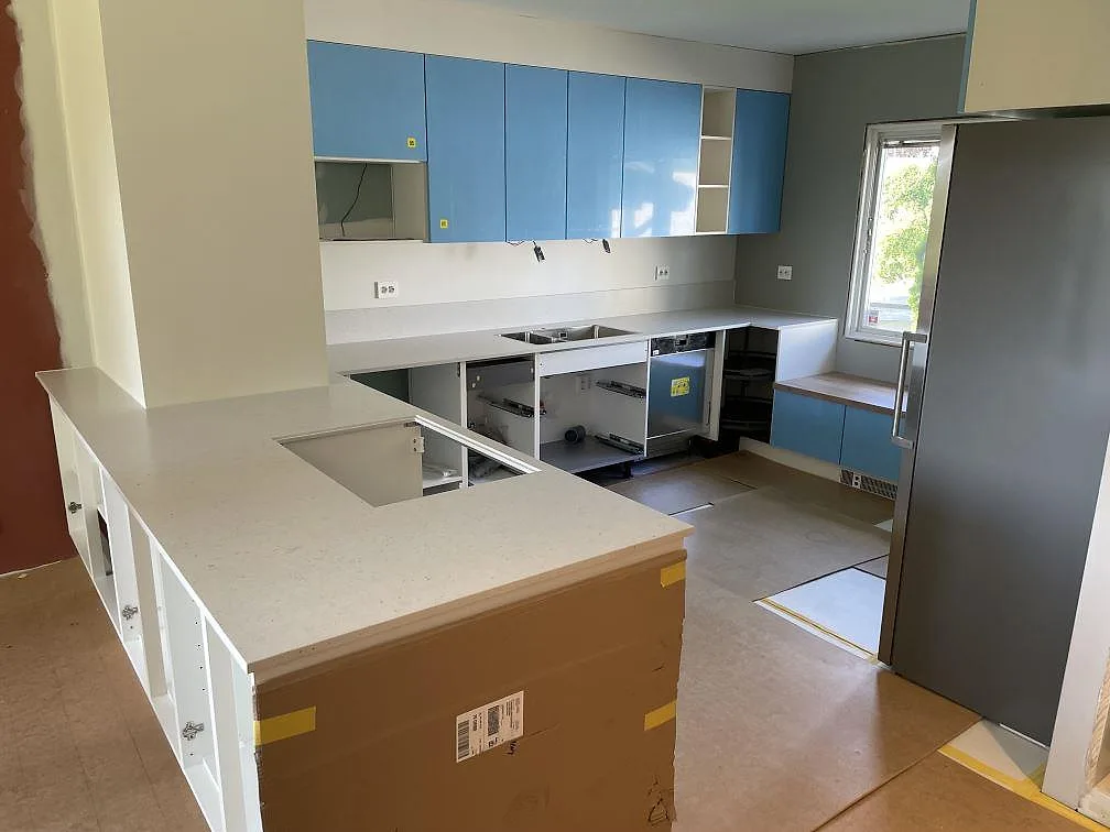 Köksbänkskiva i ljus komposit, Silestone Lime Delight, matt Mocka, med hällurtag och låg stänkkant i ett kök under montering i Lindesberg.