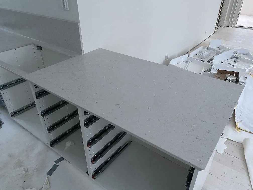 Köksö i ljus kvartskomposit Silestone Lime Delight, Mocka, monterad på vita köksstommar i Lund.