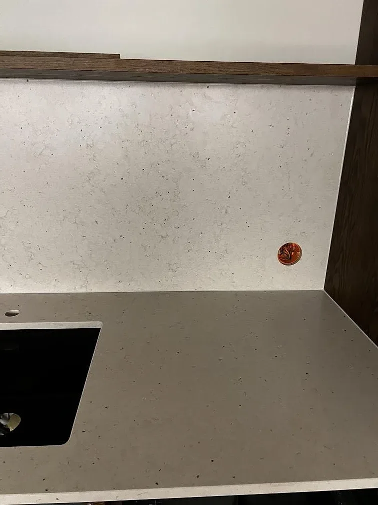 Detalj av ljus Silestone Lime Delight, matt kvartskomposit, där bänkskiva och stänkskydd möter mörk träinredning i Malmö.
