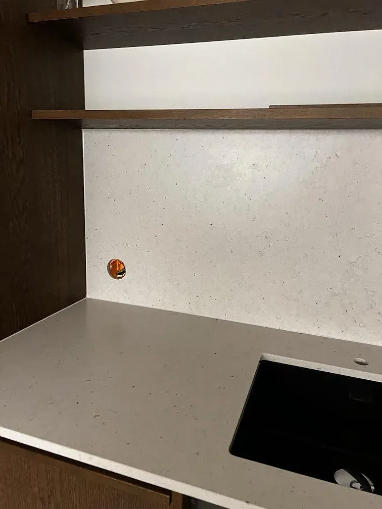 Silestone Lime Delight som ljus bänkskiva och stänkskydd mot mörk träinredning, med synlig teknisk öppning i Malmö.