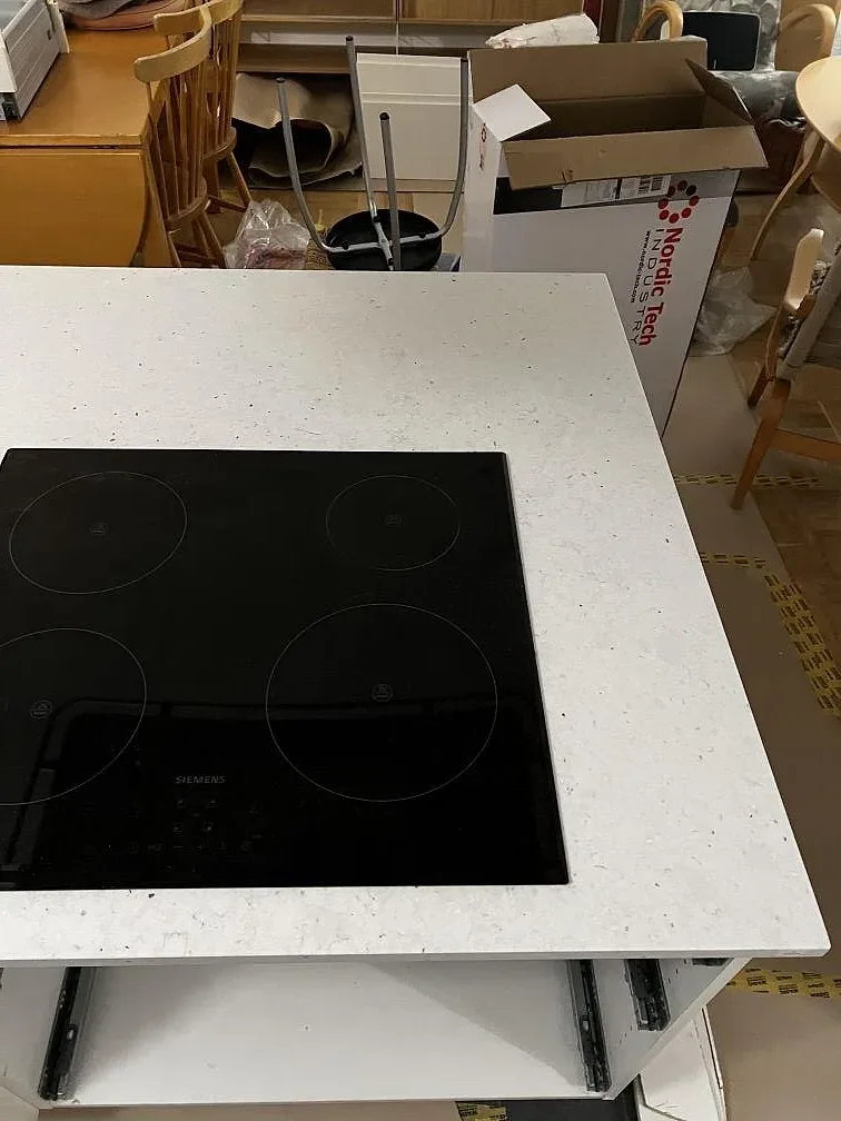 Närbild av matt Silestone Lime Delight på köksö med infälld svart spishäll och vit komposityta i Malmö.