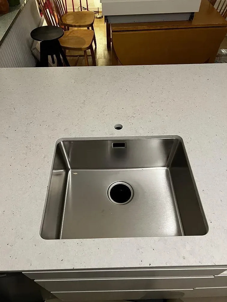 Rostfri diskho i bänkskiva av Silestone Lime Delight, matt komposit, monterad i köksö i Malmö.