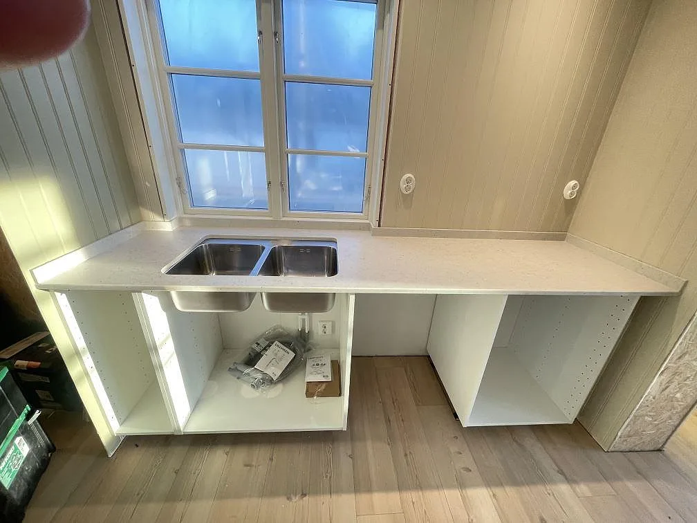 Köksbänkskiva i ljus Silestone Lime Delight under ett fönster, med nedfälld rostfri dubbelho, matt yta, i ett kök i Mörrum.