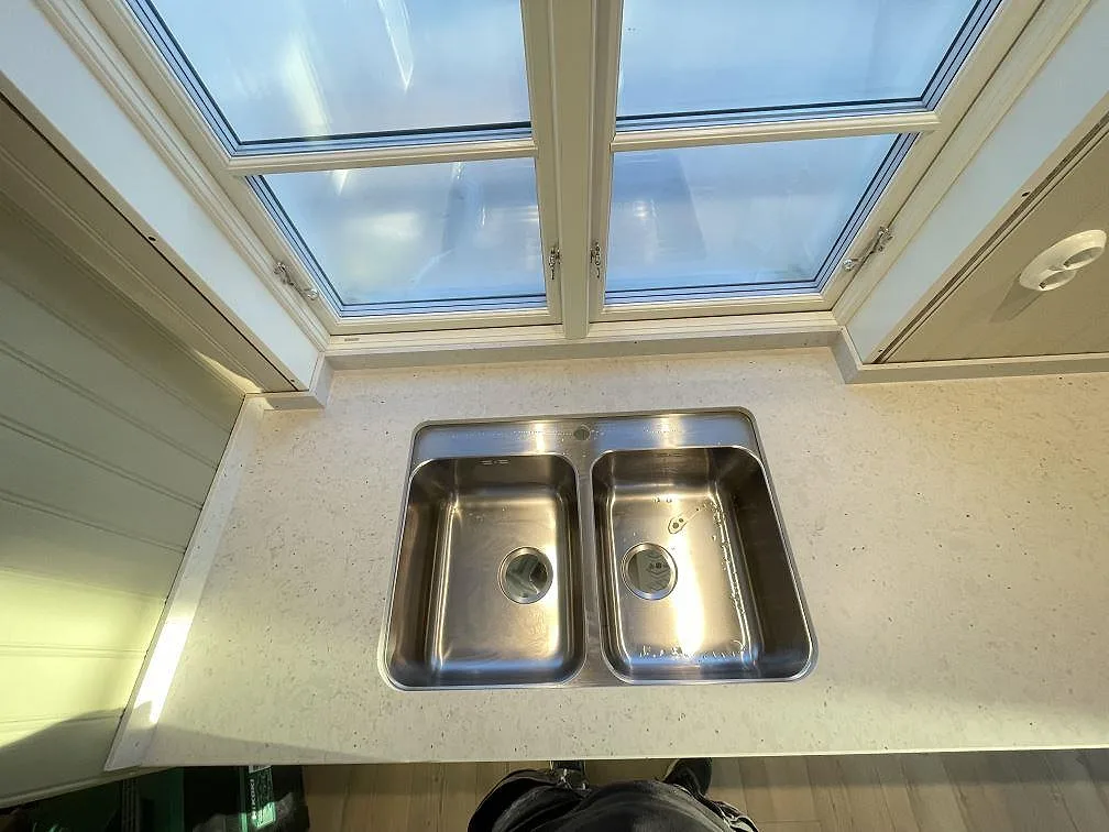 Rostfri dubbelho nedfälld i köksbänkskiva av matt Silestone Lime Delight under takfönster i ett kök i Mörrum.