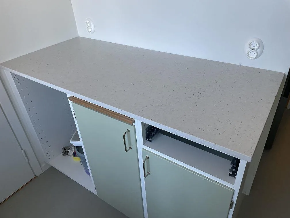 Rak bänkskiva i Silestone Lime Delight komposit, matt Mocka-yta, monterad på skåpstommar i ett kök i Stockholm.