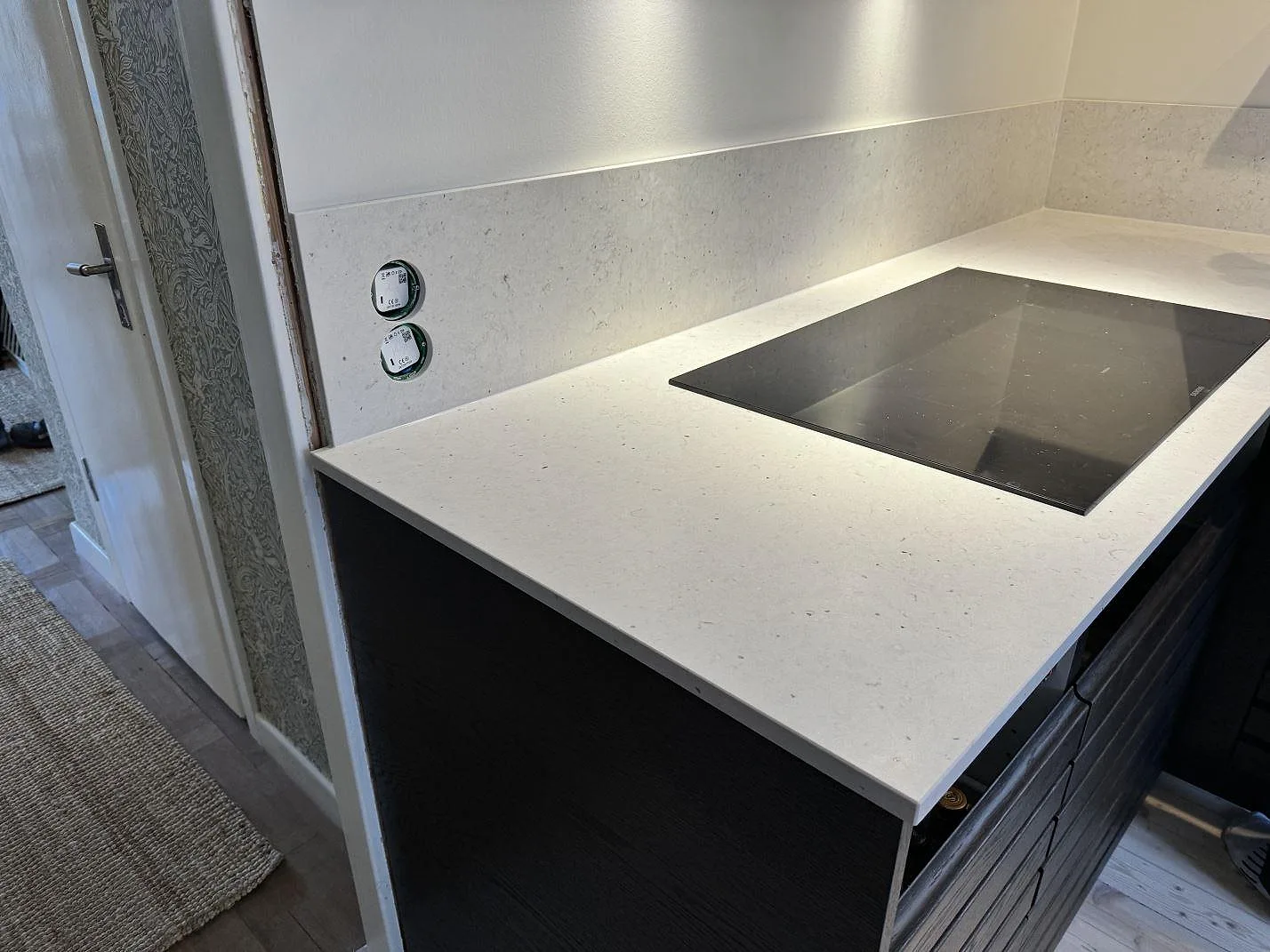 Köksbänkskiva i vit Silestone Lime Delight komposit, matt Mocka-finish, med svart häll och mörka stommar i Västra Frölunda.