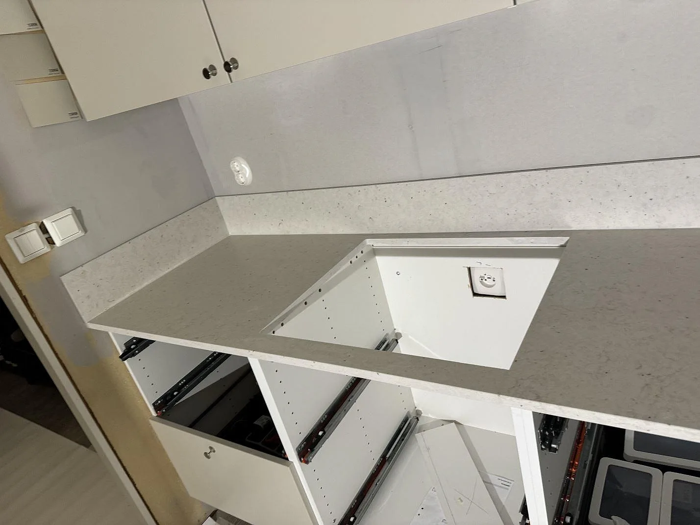 Köksbänkskiva i Silestone Lime Delight, matt kvartskomposit, med hälluttag, låg stänkkant och öppna vita köksstommar under montering i Vetlanda.