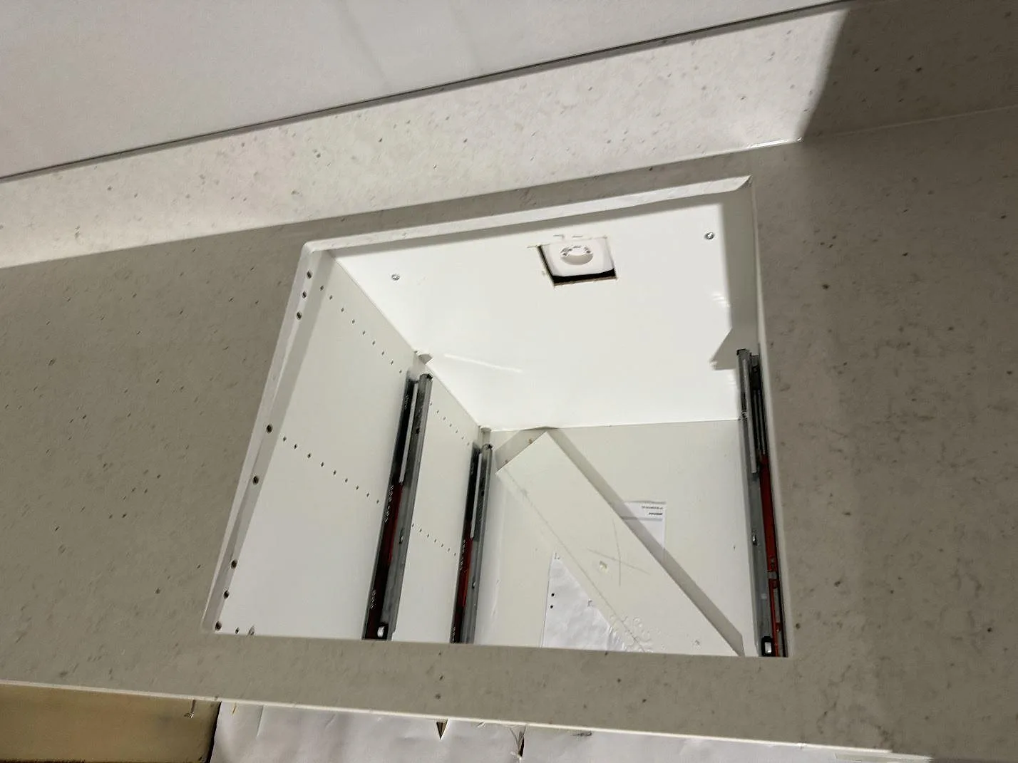 Närbild på hälluttag i en köksbänkskiva av Silestone Lime Delight, matt kompositsten, med stänkkant och vita stommar i Vetlanda.