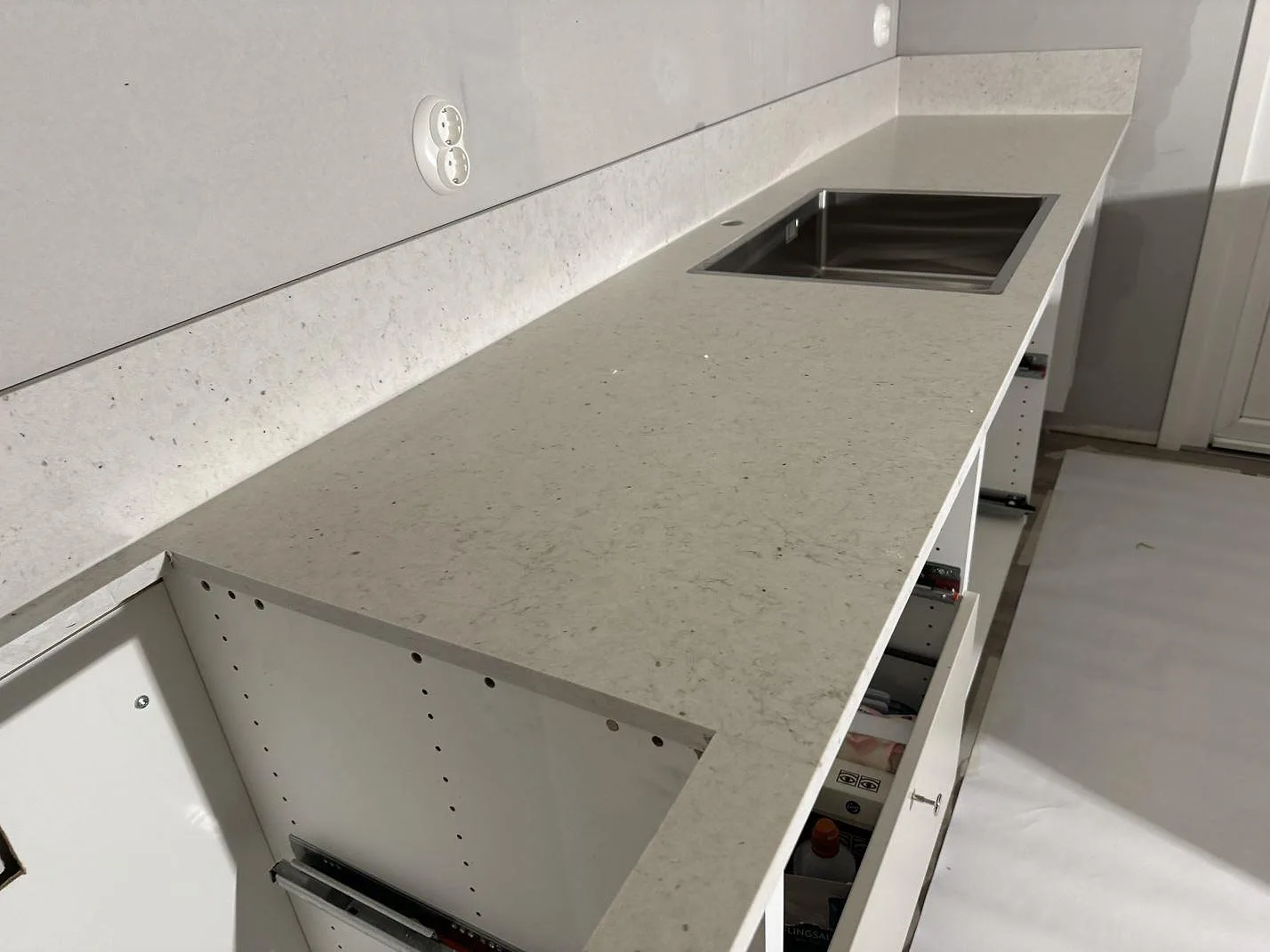 L-formad köksbänkskiva i beige Silestone Lime Delight, matt Mocka-yta, med underlimmad rostfri dubbelho och stänkkant i ett kök i Vetlanda.