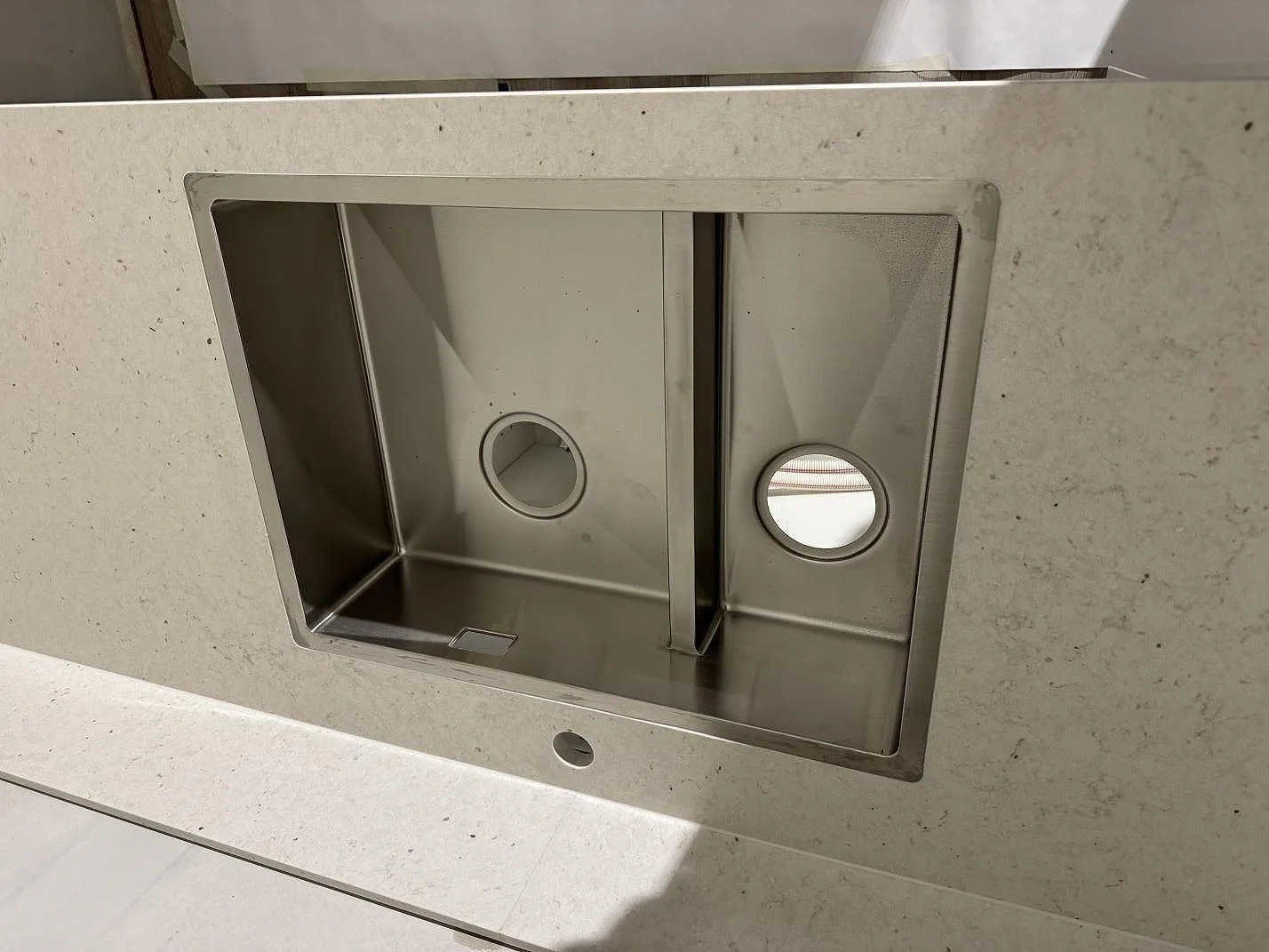 Närbild på underlimmad rostfri dubbelho i en bänkskiva av Silestone Lime Delight, matt kompositsten, i ett kök i Vetlanda.