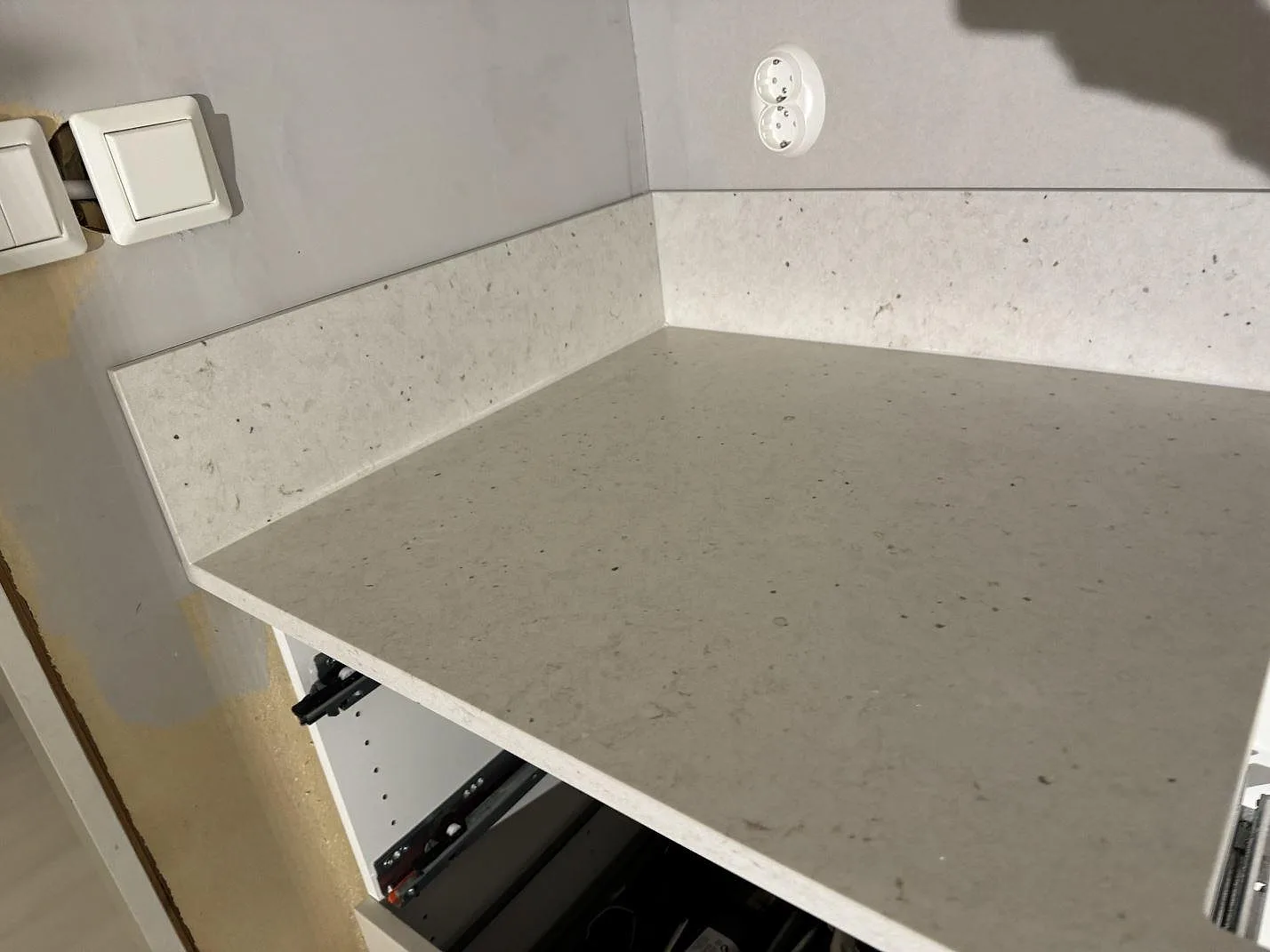 Detalj av Silestone Lime Delight som köksbänkskiva och låg stänkkant, matt beige kvartskomposit, monterad mot vägg i Vetlanda.