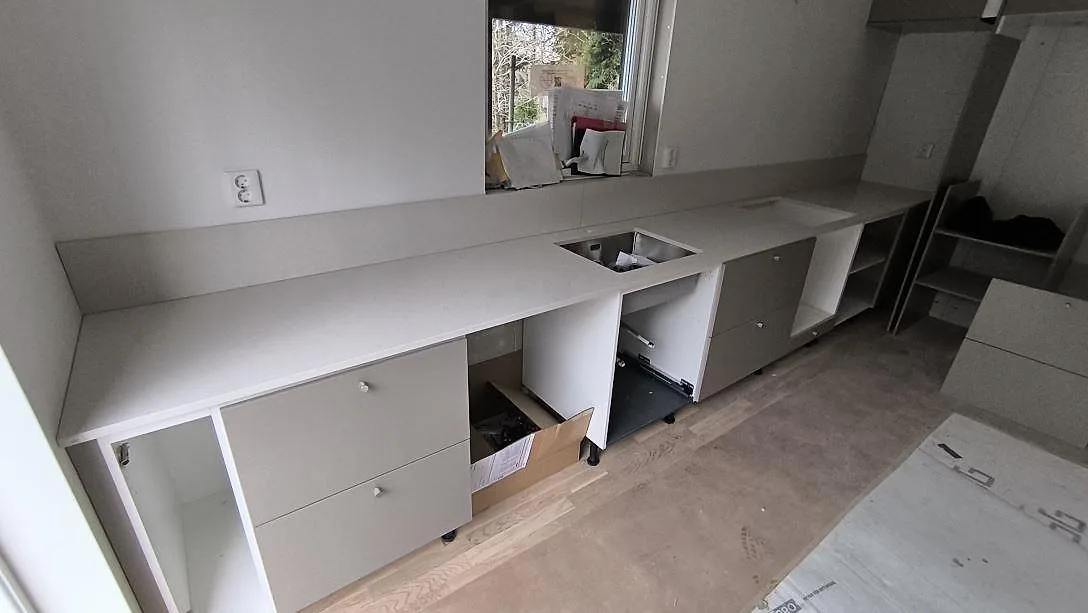 Köksbänkskiva i ljus Silestone Linen Cream, polerad komposit, med rektangulärt urtag och låg stänkkant i ett kök i Åkersberga.