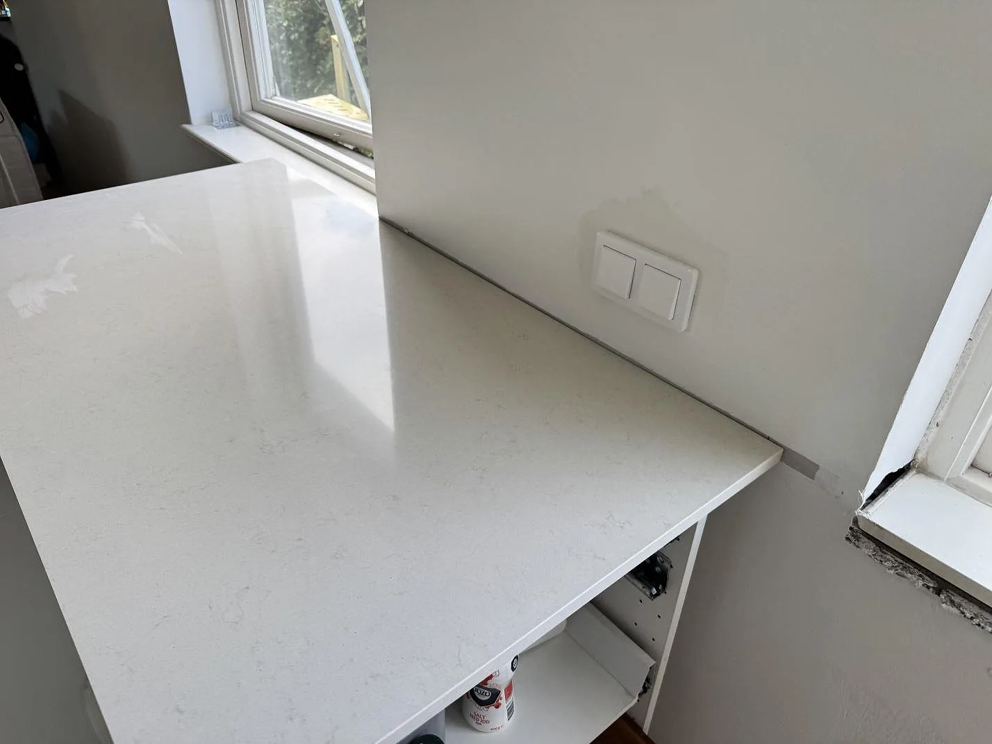 Fönsternära arbetsyta i polerad Silestone Linen Cream, ljus kvartskomposit, med diskret ådring i ett kök i Bunkeflostrand.