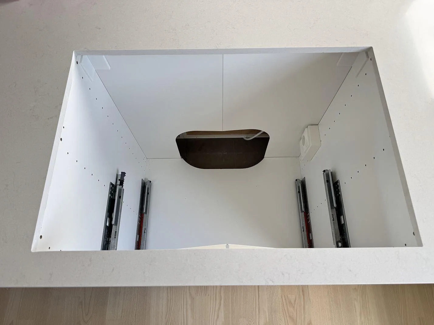 Ovanifrånbild av köksö med polerad Silestone Linen Cream, kvartskomposit, och stort urtag i stenen i Bunkeflostrand.