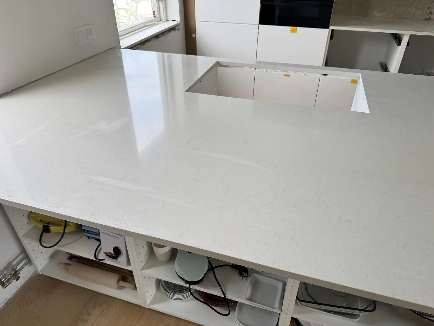 Köksbänkskiva i polerad Silestone Linen Cream, ljus kvartskomposit, med stort urtag i köksön i Bunkeflostrand.