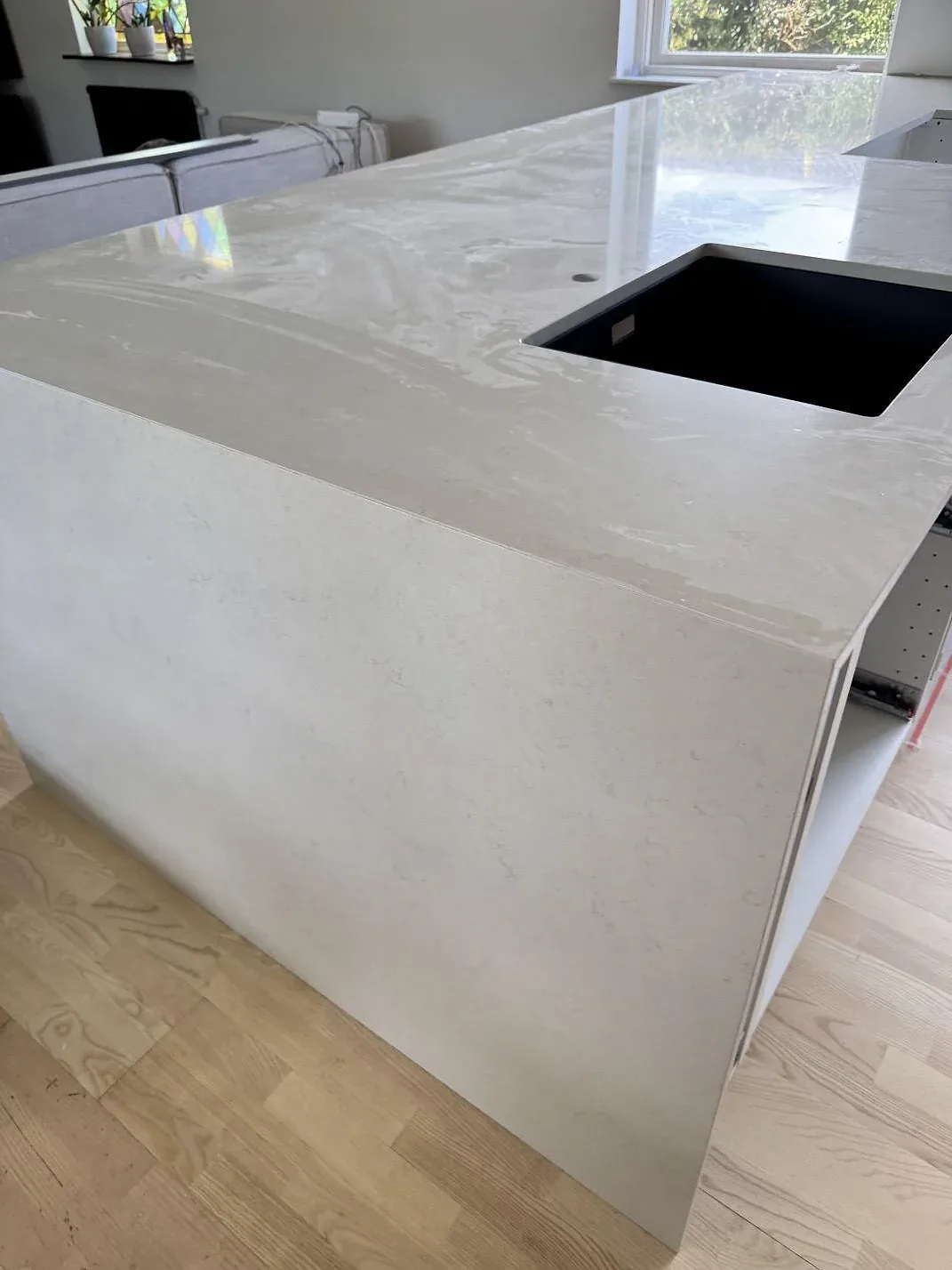 Närbild på polerad Silestone Linen Cream, kvartskomposit, med mörk diskho och ljus ådring på köksön i Bunkeflostrand.