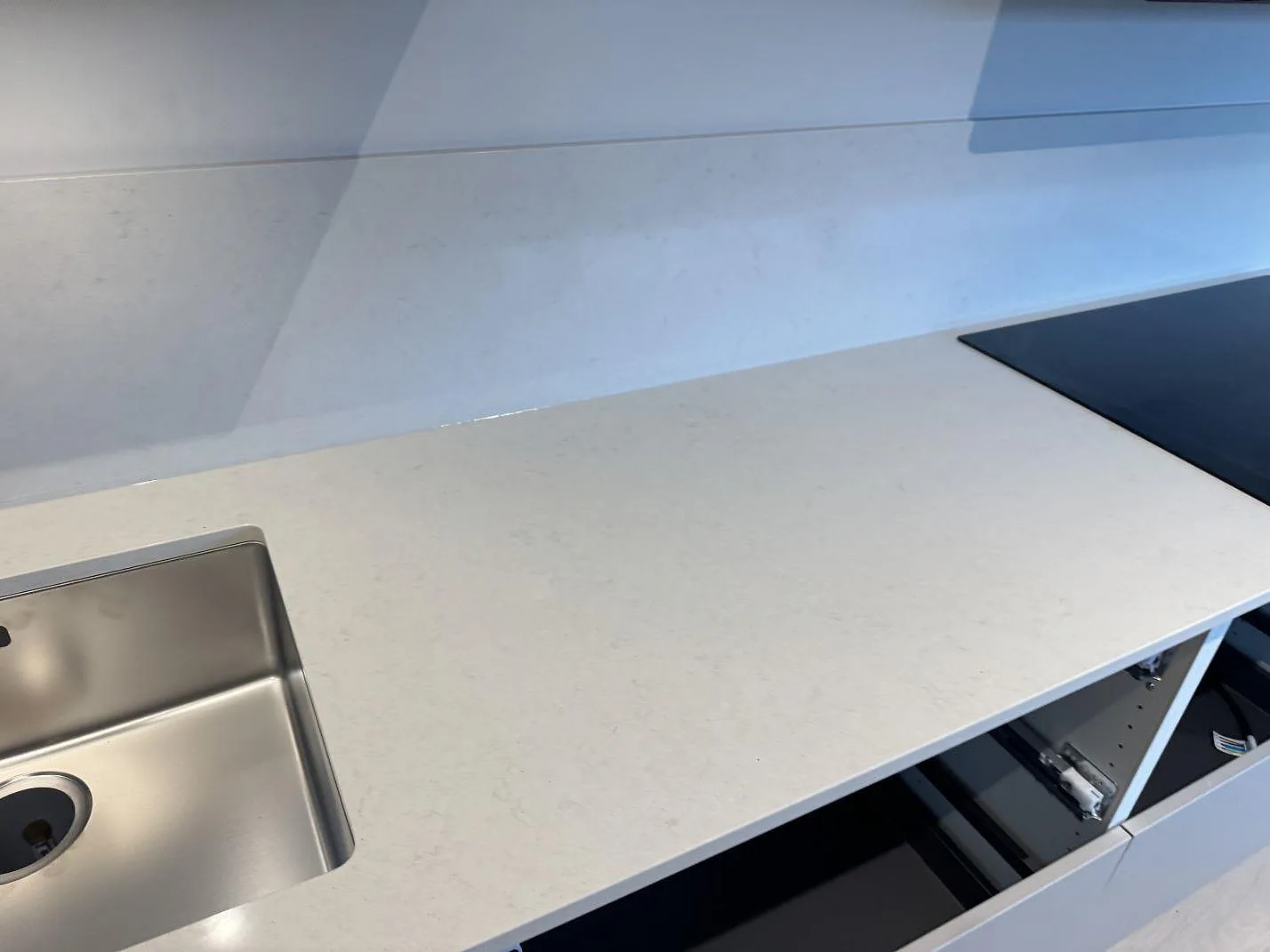 Köksbänkskiva i polerad Silestone Linen Cream mellan rostfri diskho och svart häll i Bunkeflostrand.