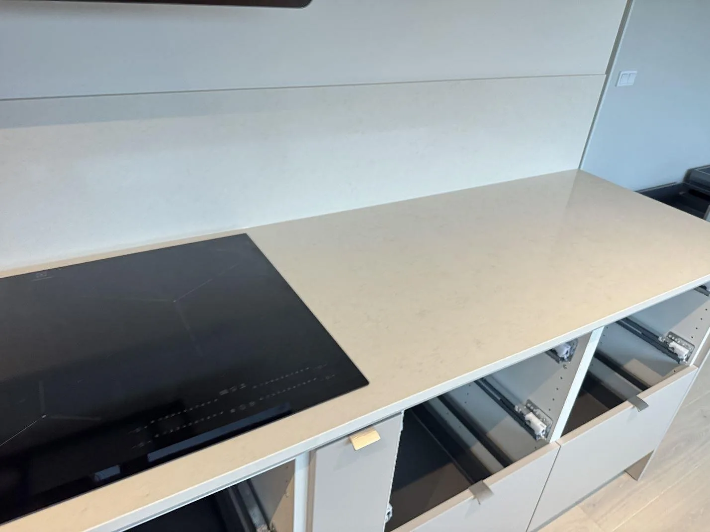Lång bänkskiva i polerad Silestone Linen Cream med häll och ljusa köksstommar under montering i Bunkeflostrand.