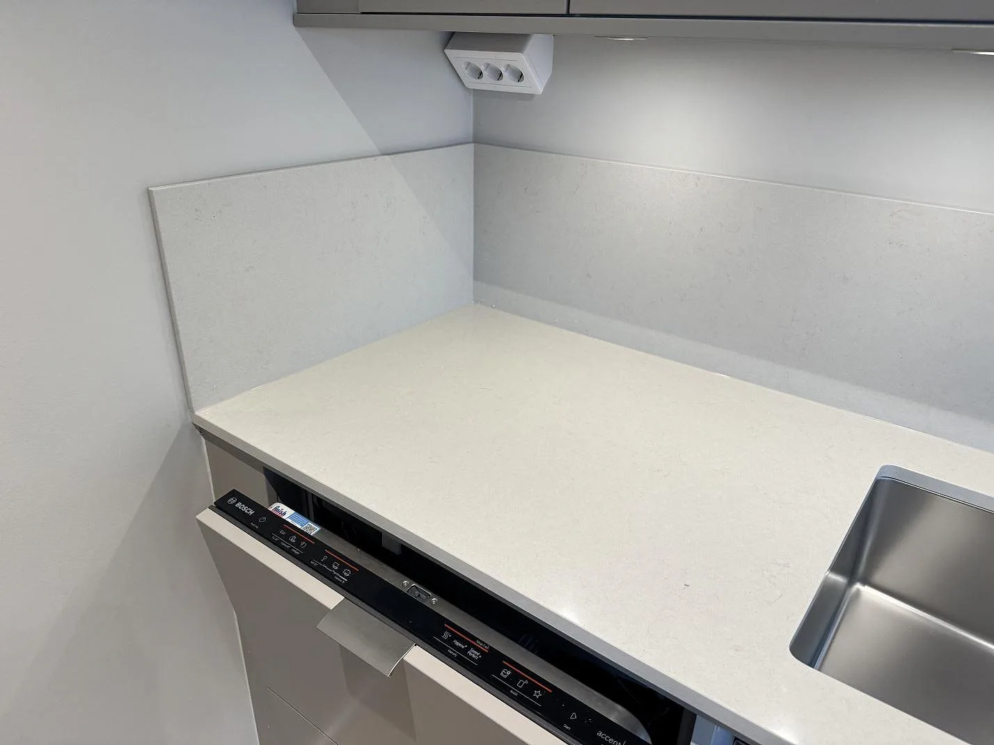 Polerad kompositbänkskiva i Silestone Linen Cream med stänkskydd och rostfri diskho i Bunkeflostrand.