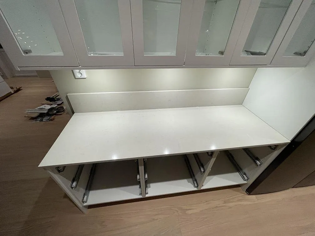 Rak väggbänk i polerad Silestone Linen Cream med låg stänkkant och öppna skåpstommar i Falun.
