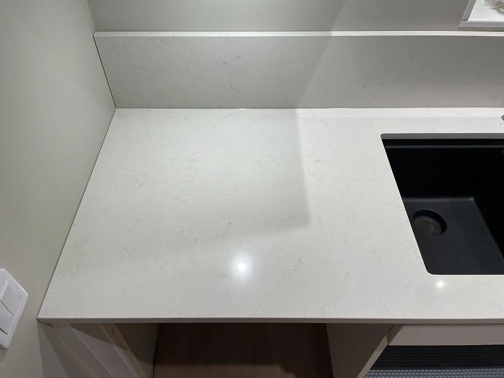 Diskhozon i polerad Silestone Linen Cream med svart ho och uppvikt stänkkant i ett kök i Falun.