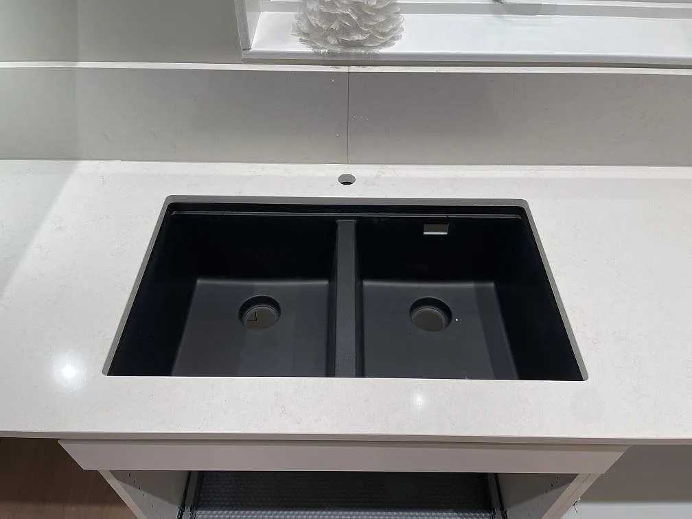Närbild på svart dubbelho i köksbänkskiva av polerad Silestone Linen Cream i Falun.