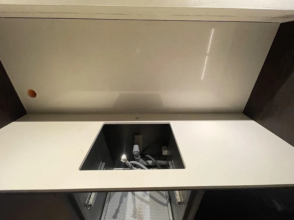 Närbild på polerad Silestone Linen Cream som bänkskiva och stänkskydd med central öppning i ett kök i Hägersten.