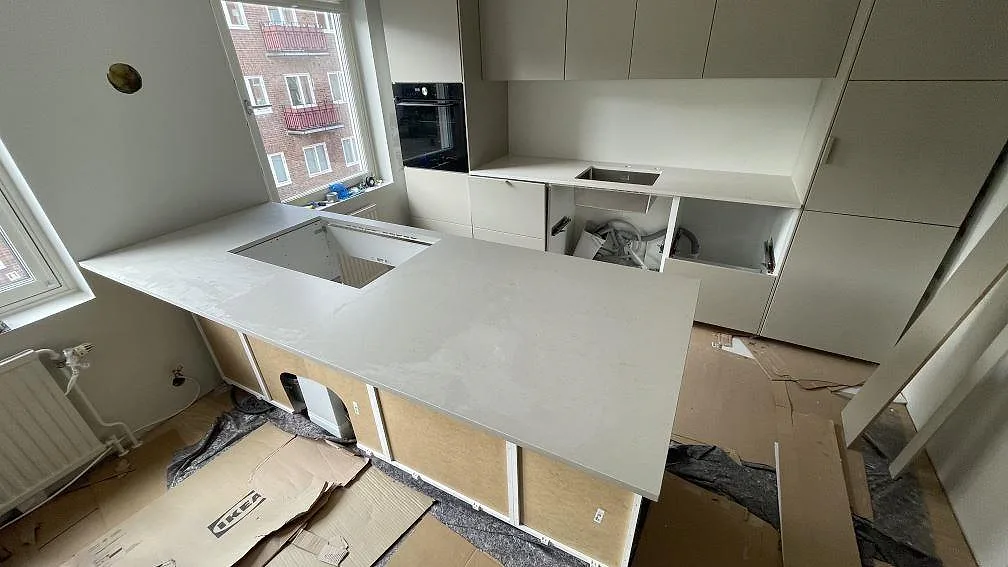 Köksbänkskiva och köksö i matt Silestone Linen Cream, 20 mm, under montering i ett ljust kök i Helsingborg.