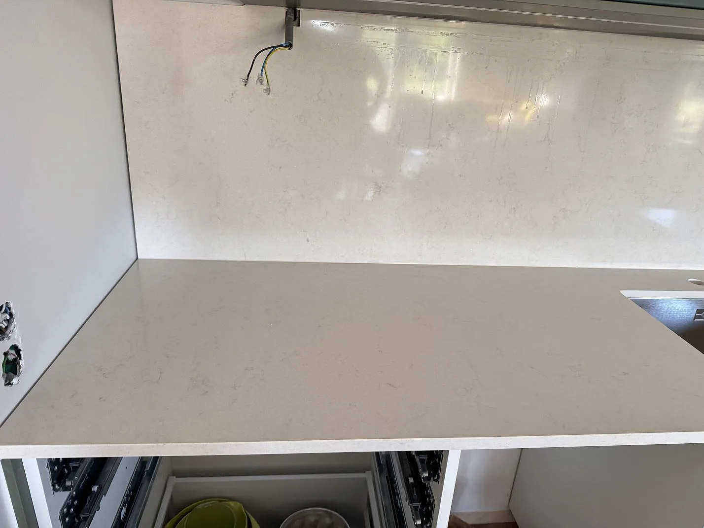 Ljus polerad Silestone Linen Cream som köksbänkskiva med stänkskydd och synlig diskhokant i ett kök under montering i Hjärup.