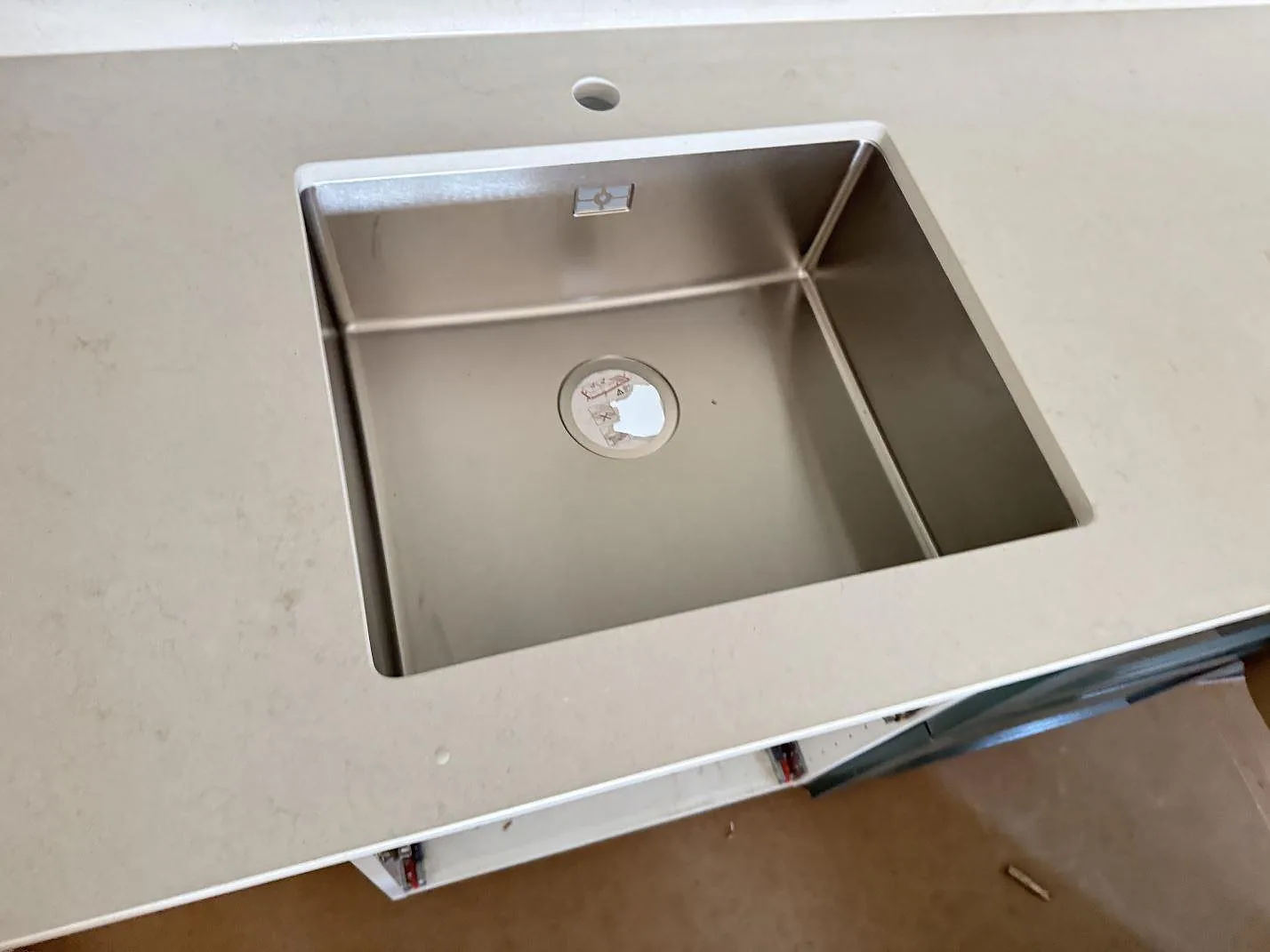Närbild på rostfri diskho i polerad Silestone Linen Cream, ljus kvartskomposit med diskret marmorering i ett kök i Hjärup.