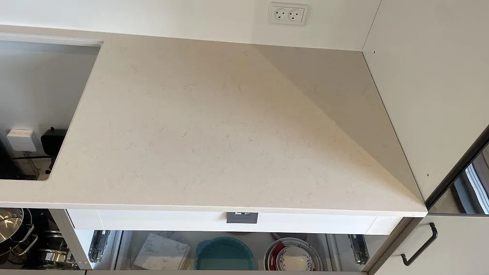 Höger sida av väggbänkskiva i polerad Silestone Linen Cream med diskret ådring och ljusa skåp i Hornslet.